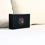 La Love Box noire est décorée au centre avec des symboles représentant le jeu et l'amour : un cœur, un triangle, un carré et une croix.