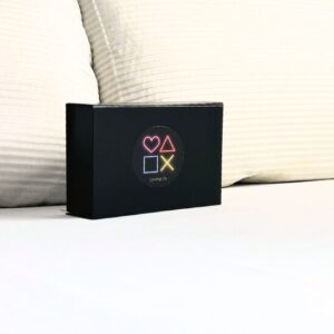 La Love Box noire est décorée au centre avec des symboles représentant le jeu et l'amour : un cœur, un triangle, un carré et une croix.
