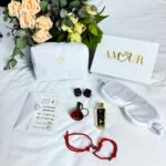 La Love Box Amour est présentée dans un élégant coffret blanc, orné au centre du mot "Amour" gravé en or, intégrant le logo de la marque Loving Up. Elle est accompagnée de tous ses produits contenus à l'intérieur. Pour compléter la présentation, un magnifique bouquet de fleurs est déposé à côté du coffret.