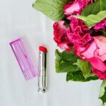 Image du rouge à lèvres vibrant de couleur rose bonbon accompagnée d'un joli bouquet de roses.